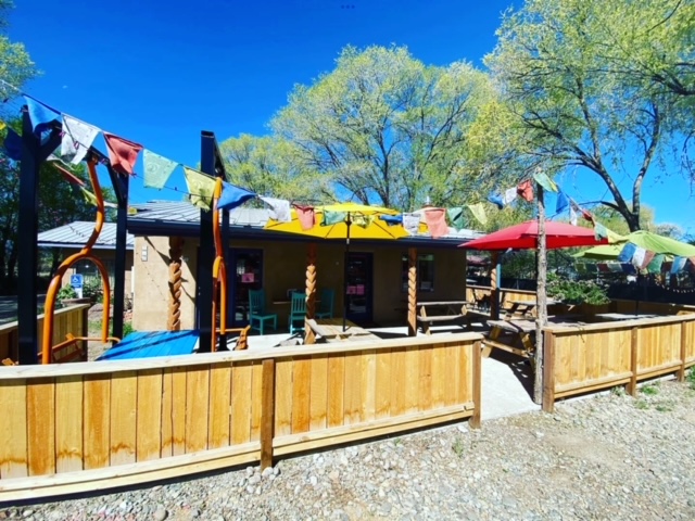 The exterior and patio of Taos Pizza Out Back restaurant.